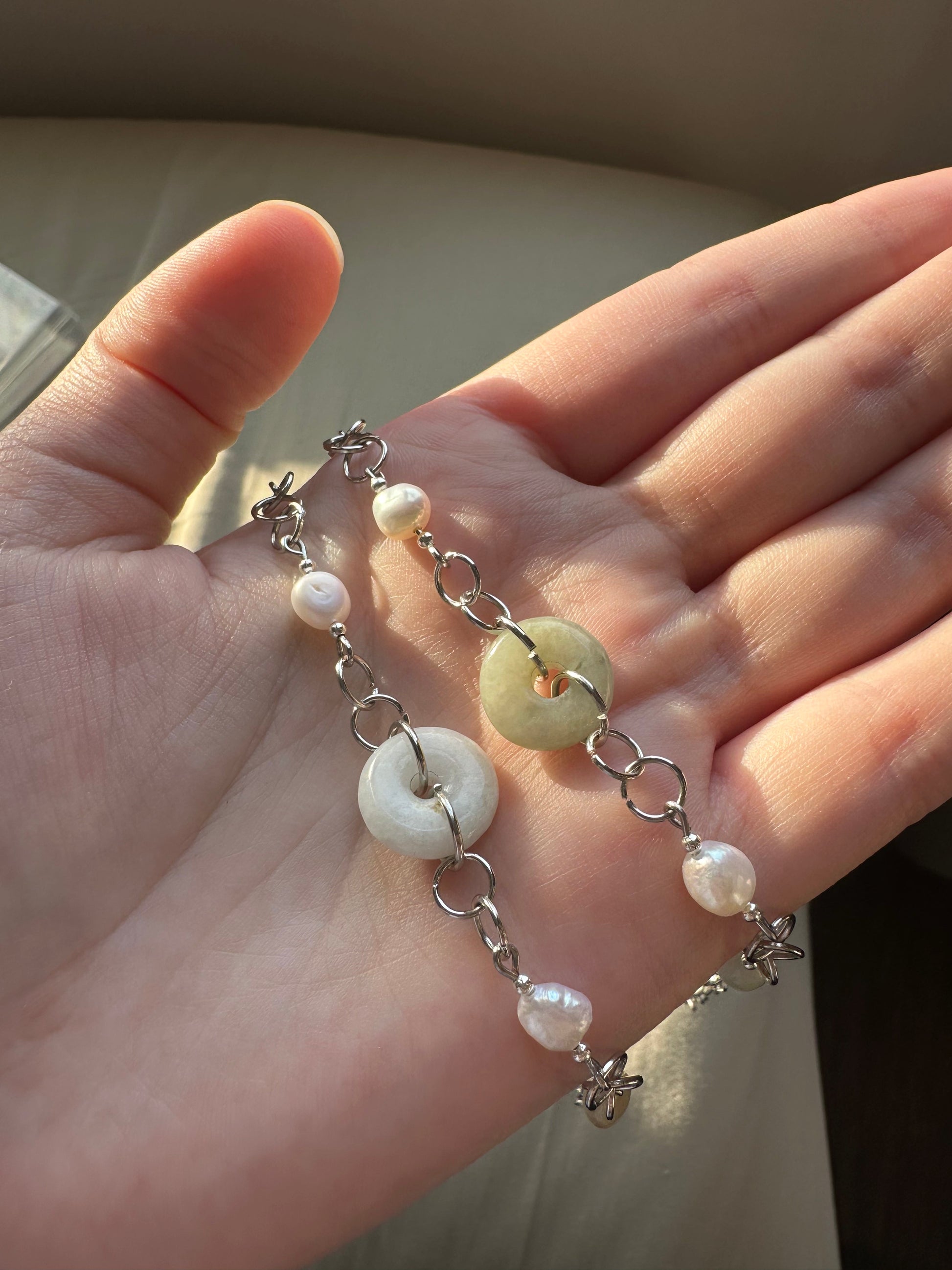 hand holding a jade and pearl silver bracelet