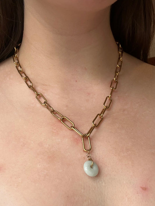 Gold chain with a pearl pendant on a person's neck