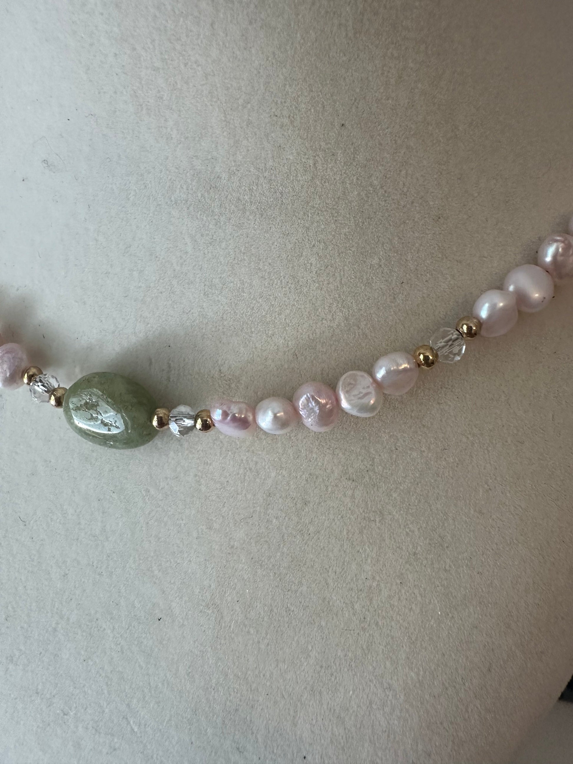 Necklace with pearls and a green bead on a light background